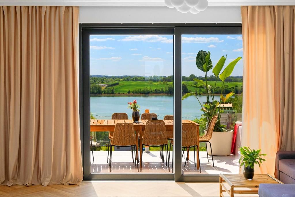 ChrostkowoにあるChojno 31i- dom wypoczynkowy przy jeziorze z jacuzziのテーブルと大きな窓のあるダイニングルーム