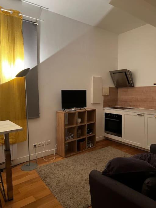 Una sala de estar con un sofá y una cocina. en Studio design aux portes de Paris, en Gennevilliers