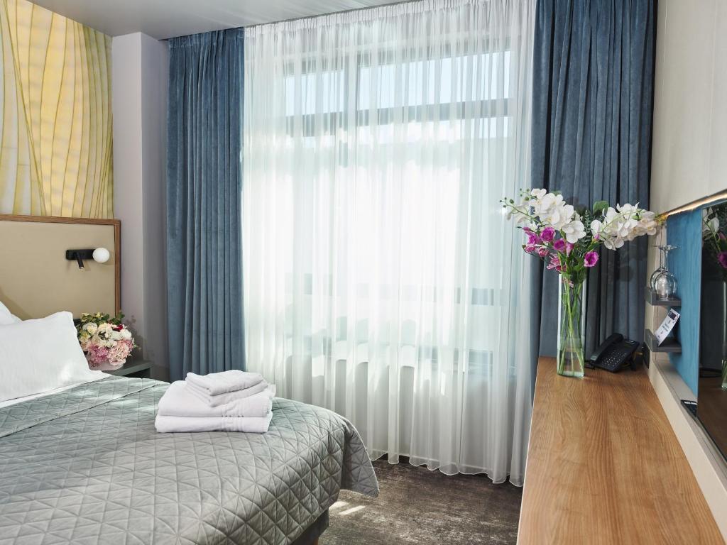 a bedroom with a bed and a vase of flowers at Hotel EMD in Bacău