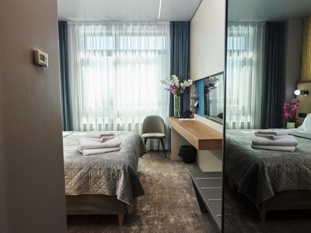 a hotel room with two beds and a desk and a mirror at Hotel EMD in Bacău