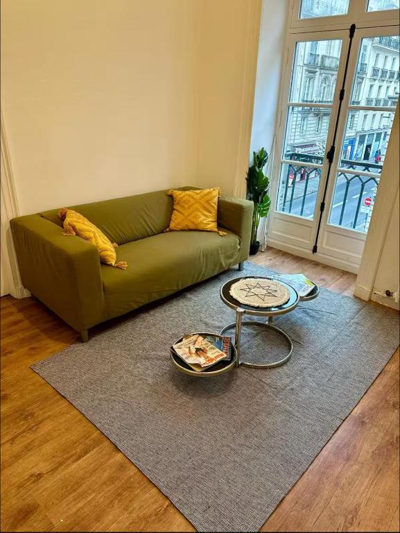 un salon avec un canapé vert et une table dans l'établissement T5 Place république Rennes, à Rennes