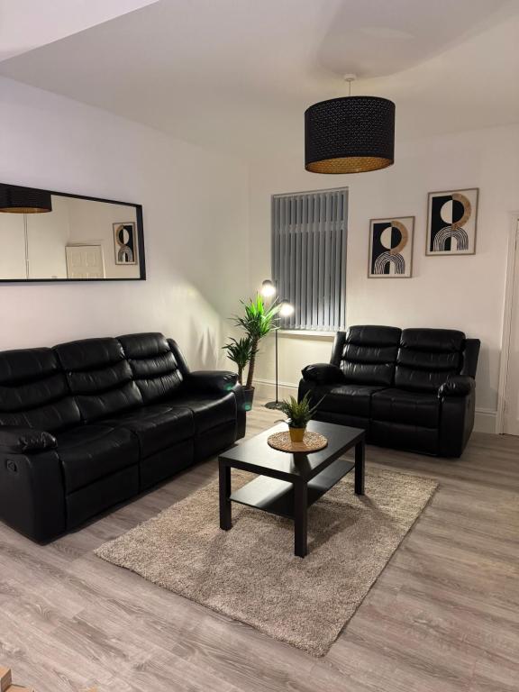 a living room with a black leather couch and a table at Cozy 3-Bedroom Home Perfect for Work & Leisure in Birmingham
