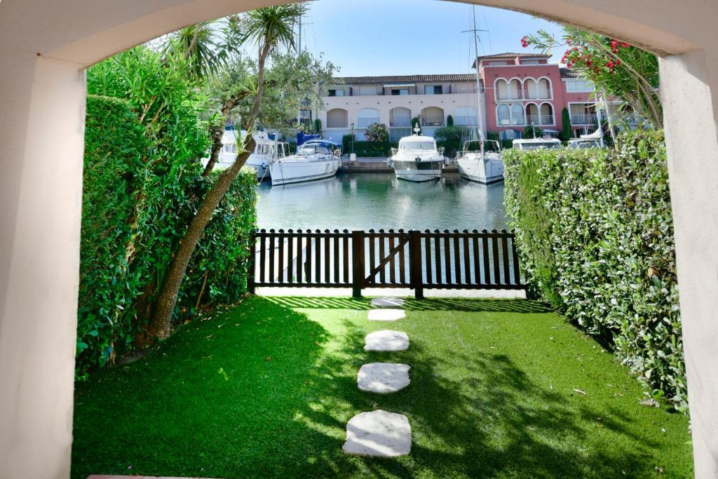 un jardin avec une clôture et des bateaux dans l'eau dans l'établissement Fisherman house with WIFI and a mooring in a private area - parking near-by, à Grimaud