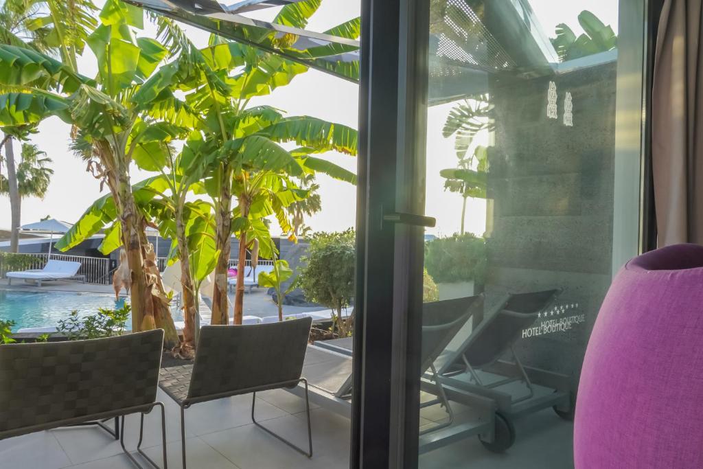 a room with a view of a pool and palm trees at La Isla y el Mar, Hotel Boutique in Puerto del Carmen