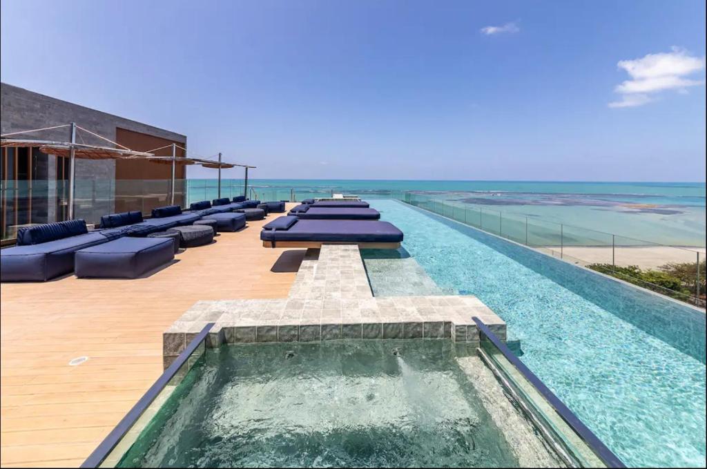 ein Schwimmbecken mit blauen Kissen auf dem Dach eines Gebäudes in der Unterkunft beira-mar pajuçara in Maceió