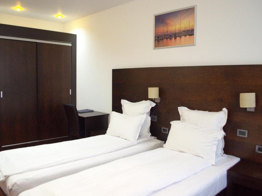 two beds in a hotel room with white pillows at Hotel EMD in Bacău