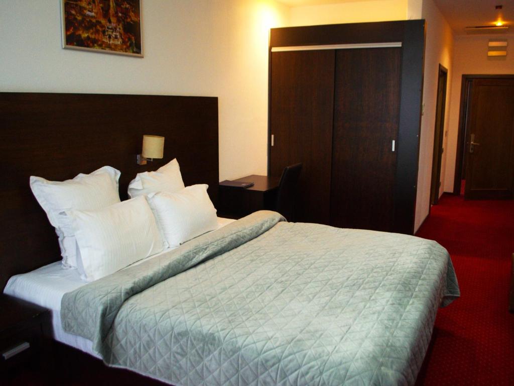 a hotel room with a large bed with white pillows at Hotel EMD in Bacău