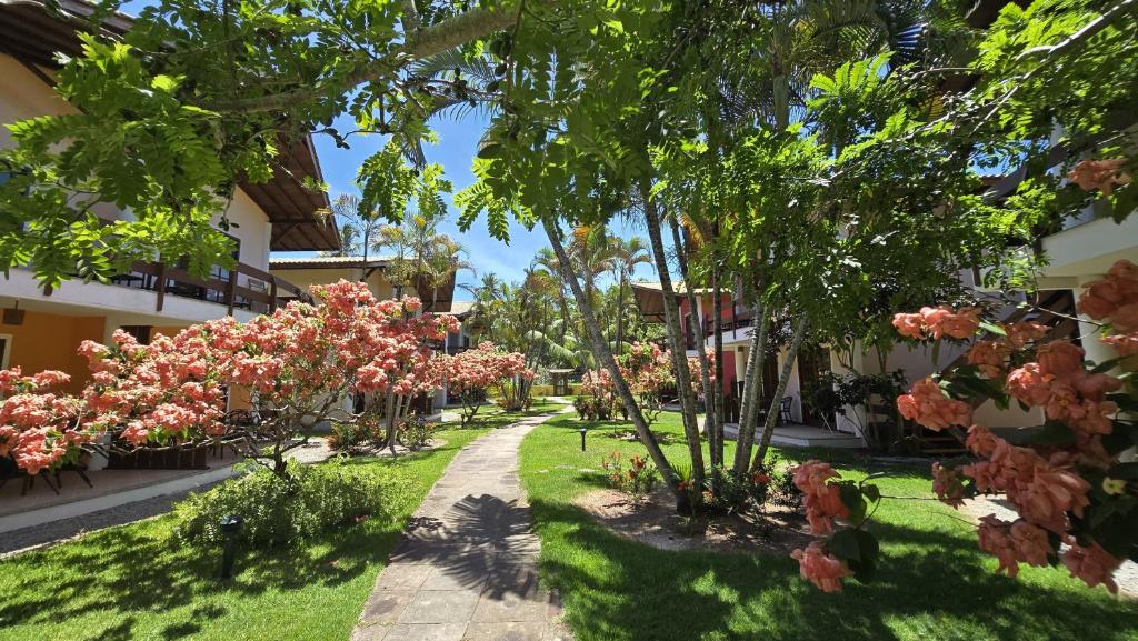 un jardin avec des arbres et des fleurs roses dans une cour dans l'établissement Casa Lírio - Beira da praia, à Porto Seguro
