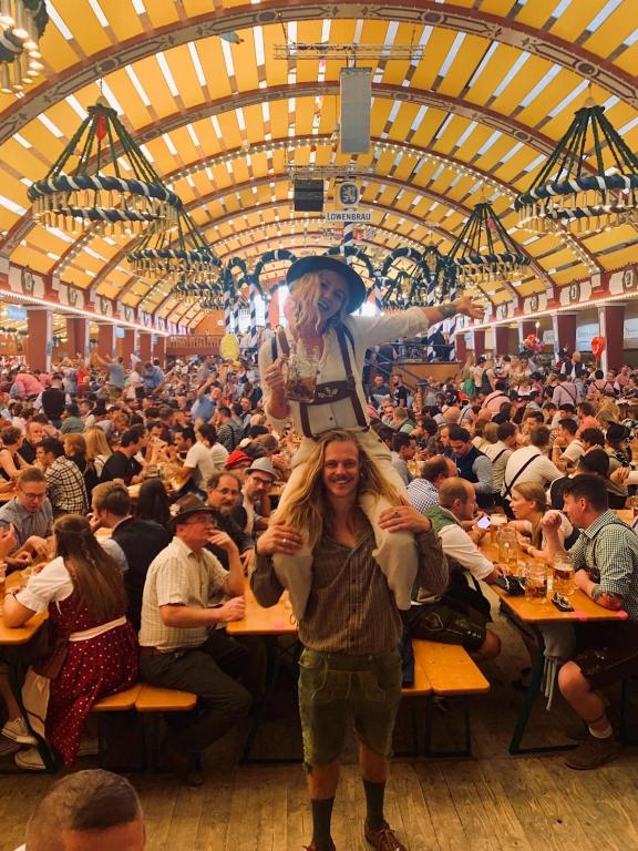 a woman standing in front of a crowd of people at tables at Løst Souls Oktoberfest Campsite in Munich