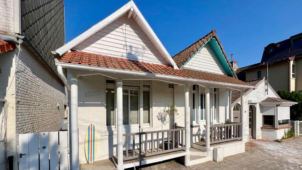 ein weißes Haus mit einer Veranda und einem Dach in der Unterkunft Riquette in Le Touquet-Paris-Plage