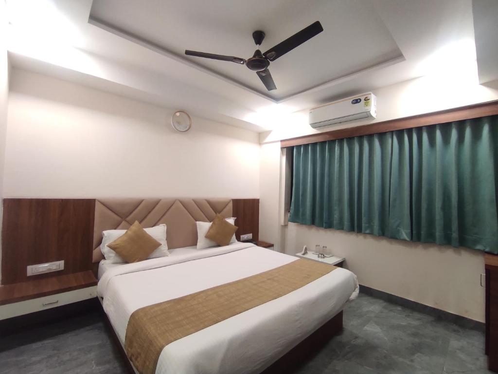 - une chambre avec un grand lit et un rideau vert dans l'établissement Hotel Earth Inn, Subhash Bridge, RTO Circle, Ahmedabad, à Ahmedabad