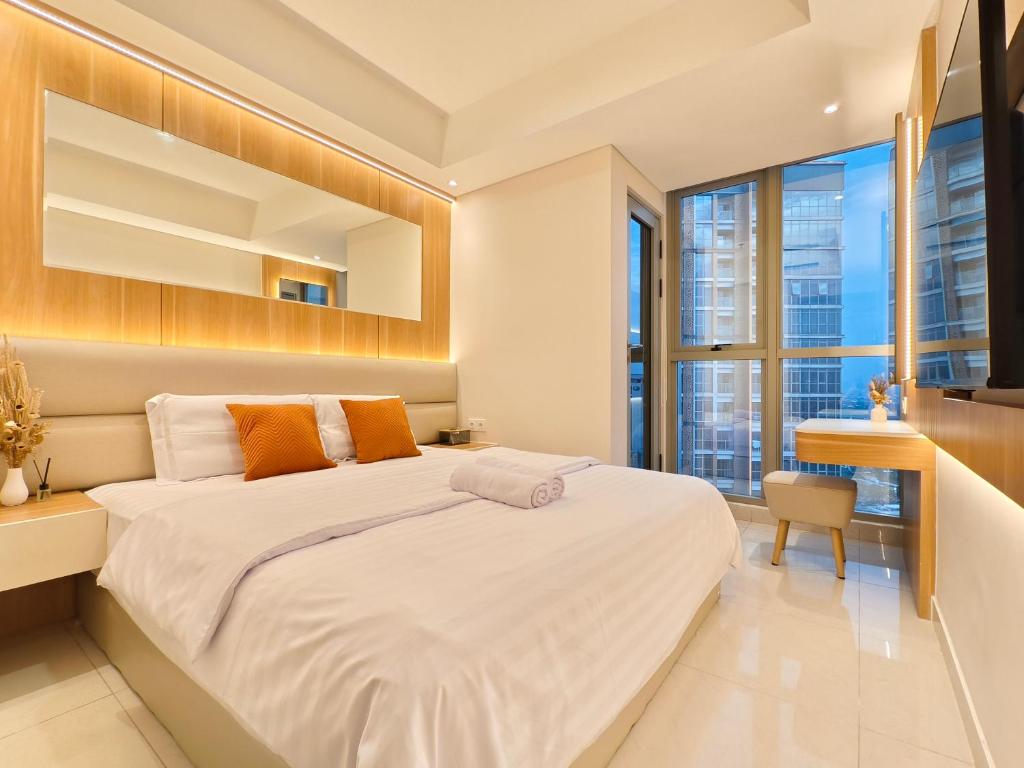 a bedroom with a large white bed with orange pillows at Studio Sea View Apartment at Gold Coast PIK by MYsweethome in Jakarta