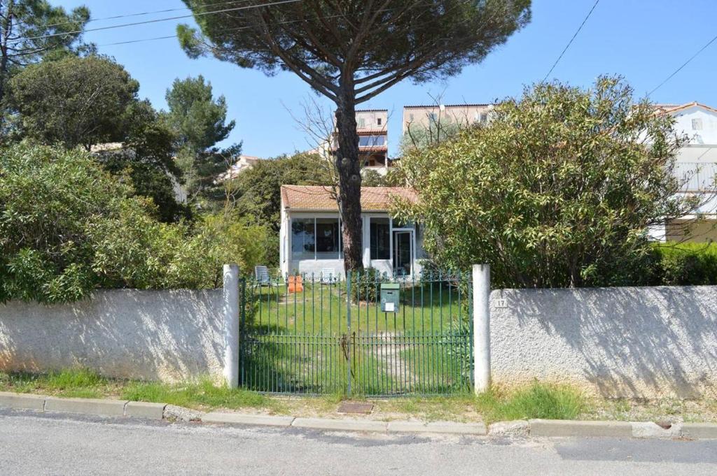 einen Zaun vor einem Haus mit einem Baum in der Unterkunft SP000-017 Maison 3 pièces - 5 couchages St Pierre la mer in Saint Pierre La Mer