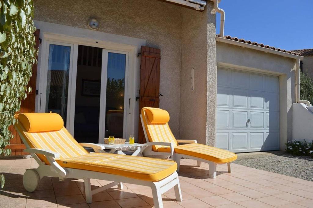 2 chaises et une table sur une terrasse avec garage dans l'établissement SP090-040 Maison 2 pièces mezzanine SAINT PIERRE LA MER, à Saint Pierre La Mer