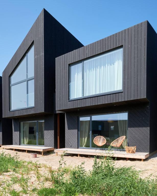 a black house with two chairs in front of it at Svencelės burė 10 in Svencelė