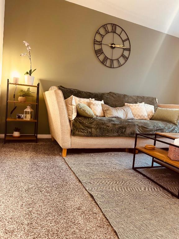 a living room with a couch and a clock on the wall at Regent Apartment - FREE PARKING in Blythe