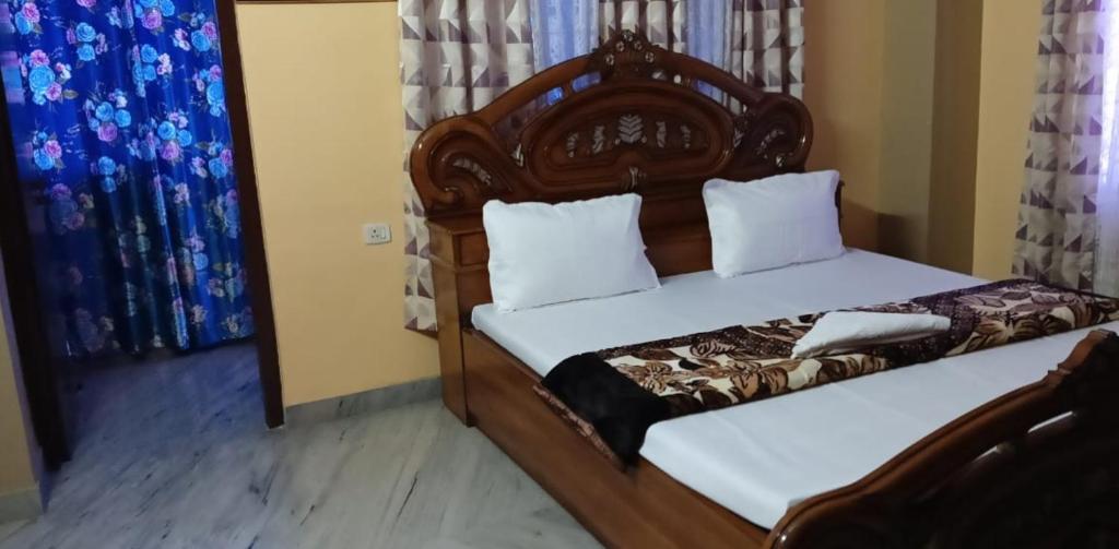 a bedroom with a bed with a wooden headboard at Goodluck Homestay in Guwahati