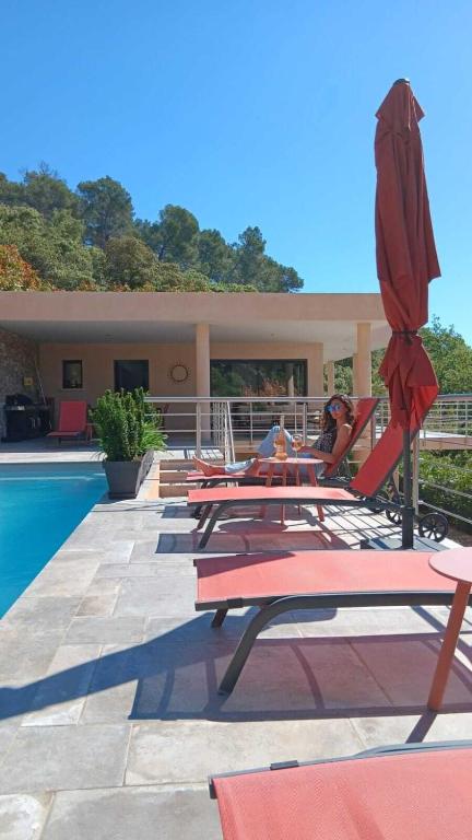 a group of chairs and umbrellas next to a pool at Les Hauts du Peireguier in La Motte