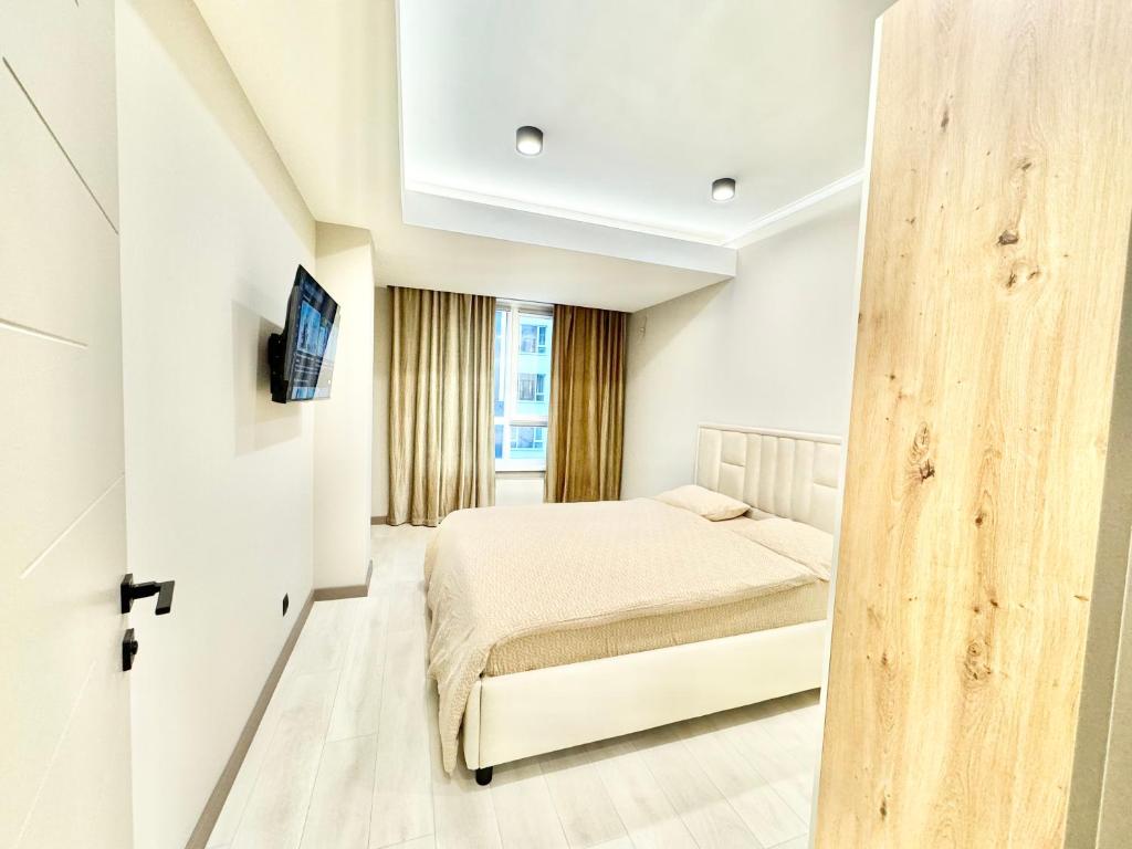 a white bedroom with a bed and a window at Замечательная новая квартира на Ботанике in Chişinău