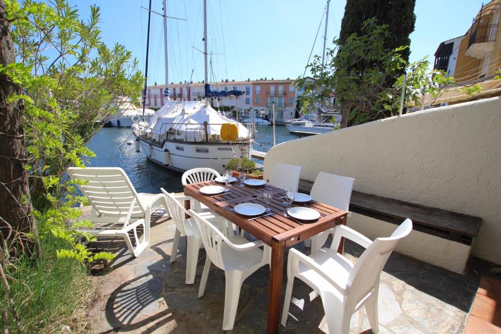 - une table et des chaises en bois sur un balcon avec un bateau dans l'établissement Fisherman house close to the beach - WIFI, à Grimaud