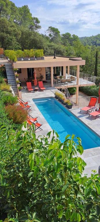 a swimming pool with chairs and a house at Les Hauts du Peireguier in La Motte