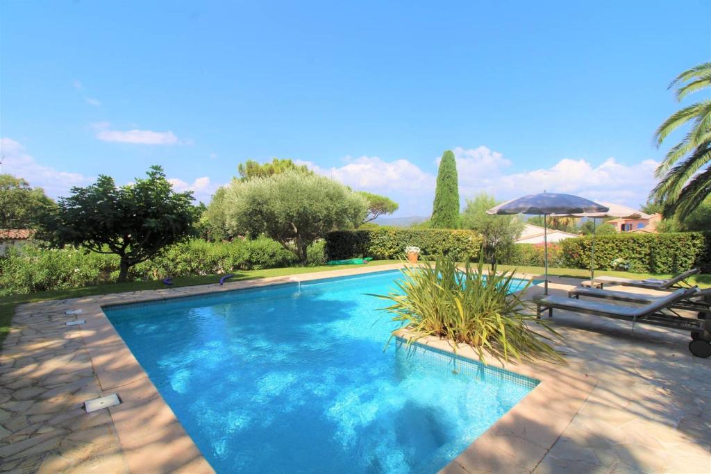une piscine avec deux chaises et un parasol dans l'établissement Villa Sanderling - A 3 km de St-Tropez - Villa climatisée avec piscine privée, à Saint-Tropez