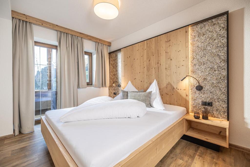 a bedroom with a white bed and a wooden wall at Appartements Liftstüberl in Alpbach