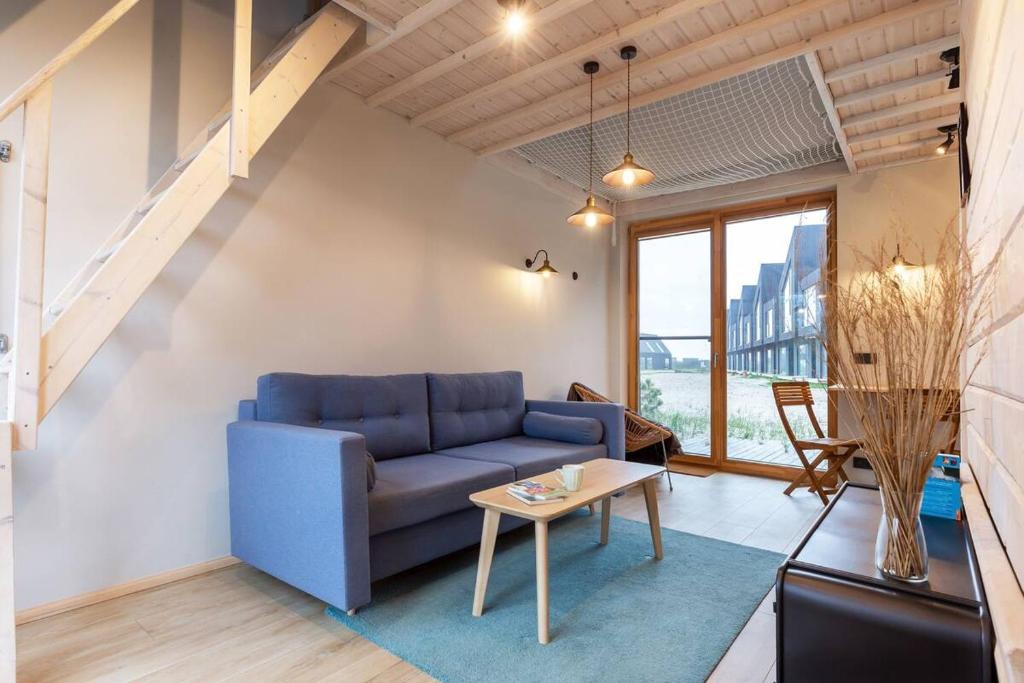 a living room with a blue couch and a table at Modern Svencelė Cottage I-Friends and Family in Svenele