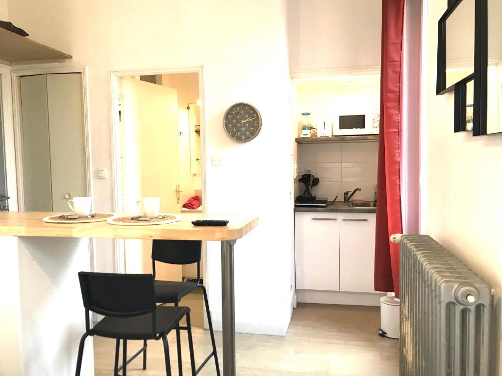 une cuisine avec une table et des chaises dans une pièce dans l'établissement LE CASTEL LILY - Calme - Face aux Parcs - Immeuble de caractère, à Vichy