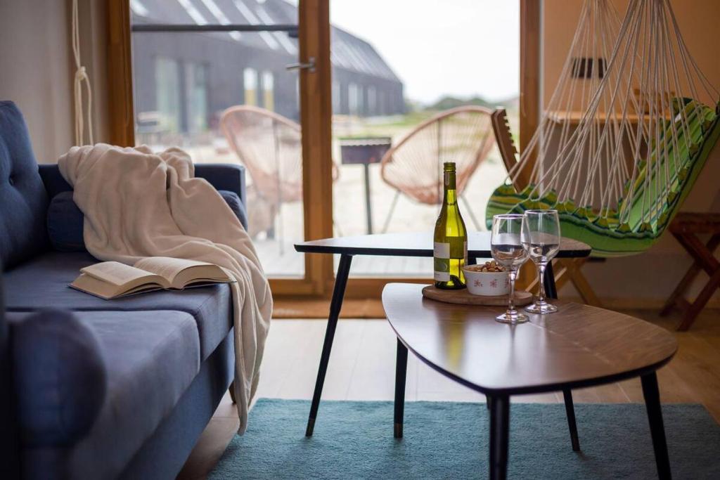 ein Wohnzimmer mit einem Sofa und einem Tisch mit Weingläsern in der Unterkunft Modern Svencelė Cottage II-Friends and Family in Svenele