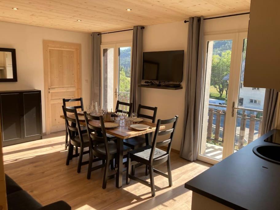 une salle à manger avec une table avec des chaises et une télévision dans l'établissement Appartement refait à neuf dans villa, à Villard-de-Lans