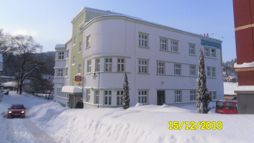 a snow covered building with a car in front of it at Hotel Grand in Tanvald