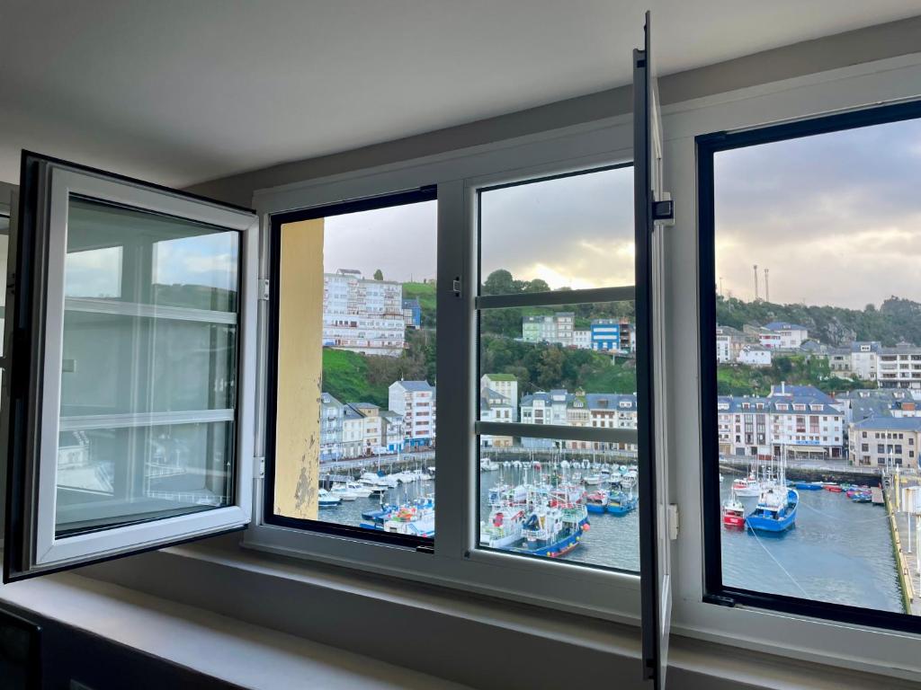 three windows in a room with a view of a harbor at Atico El Puerto in Luarca