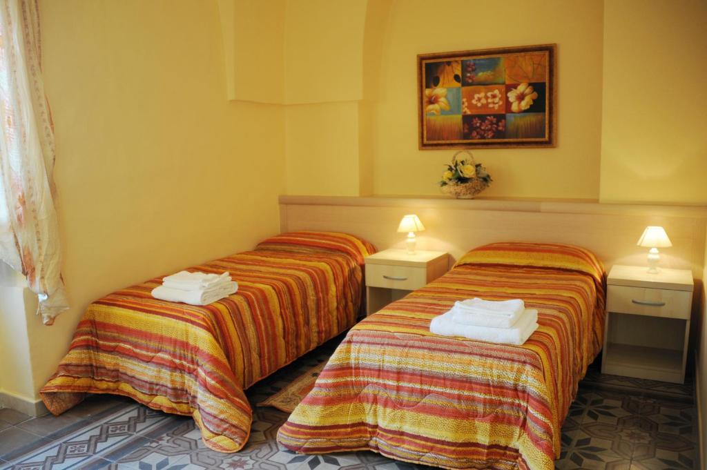 2 camas en una habitación con paredes amarillas en L'Antica Dimora, en San Pietro Vernotico