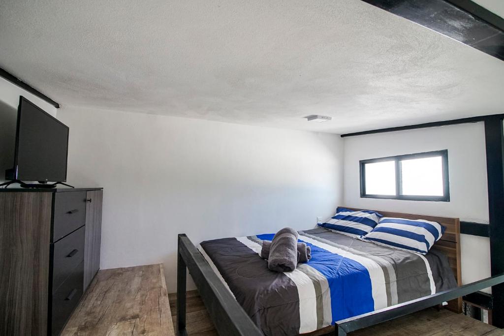 Un dormitorio con una cama con almohadas azules y blancas. en Lofts Tequisquiapan, en San Luis Potosí