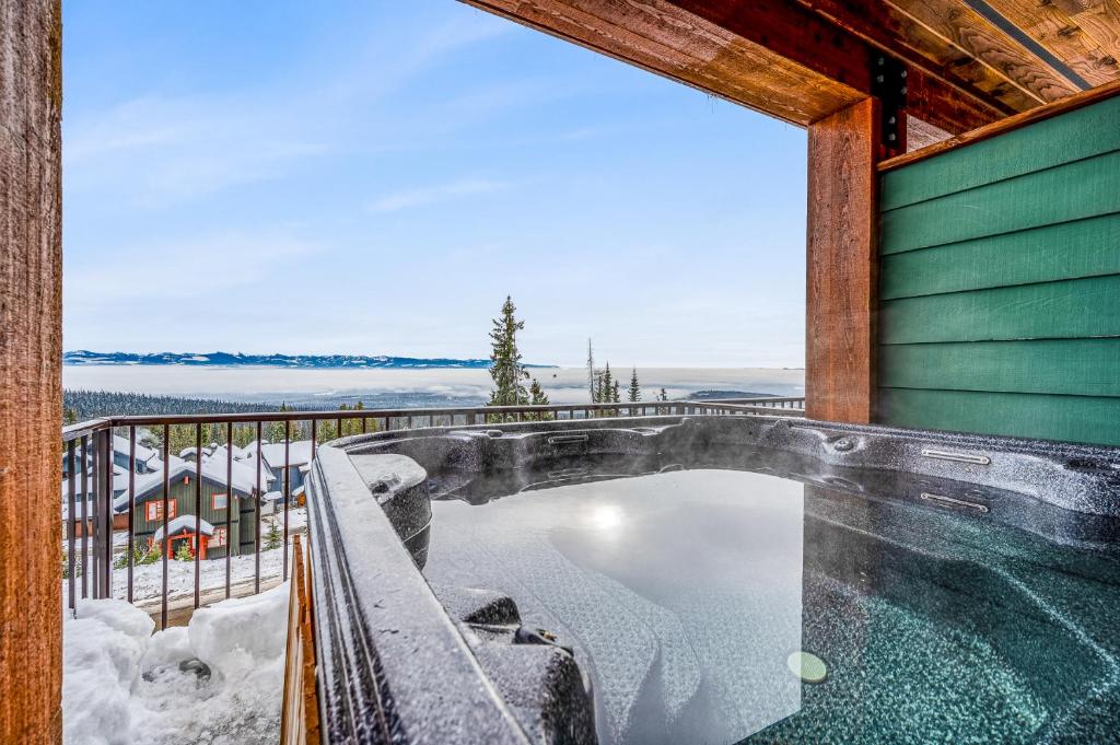 ビッグ・ホワイトにあるVista at Big White w Amazing Location and Viewの雪の家のバルコニーにホットタブがあります。