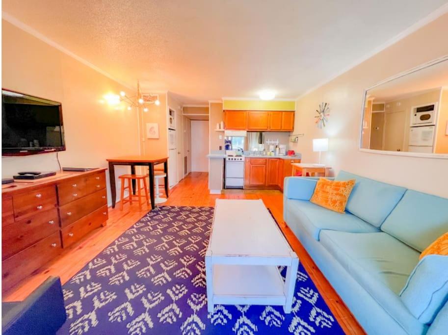 a living room with a blue couch and a kitchen at Seascape Retreat in Tybee Island