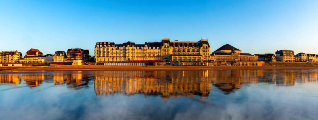 a large building with its reflection in the water at La maison du Pays d'Auge in Troarn
