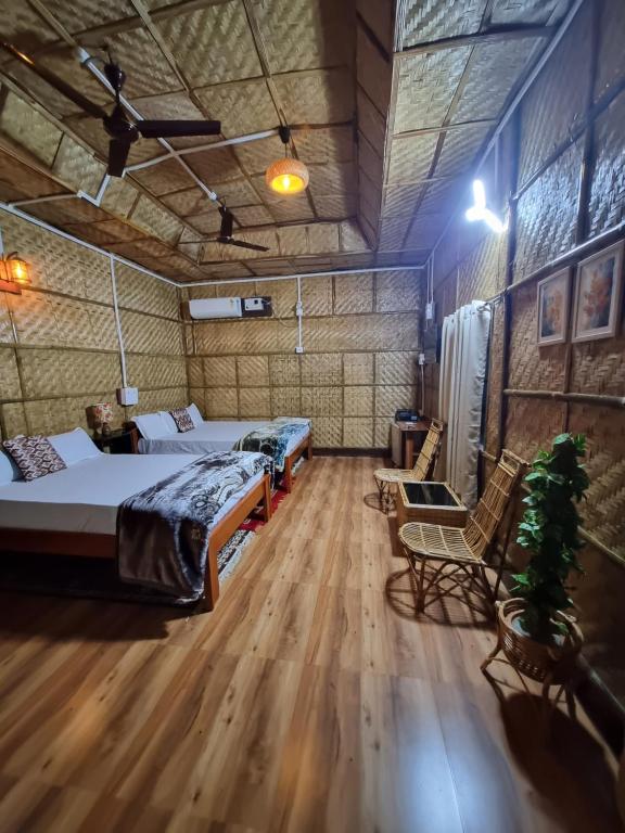 two beds in a room with wooden floors at Alohi The Cottage Homestay in Tezpur
