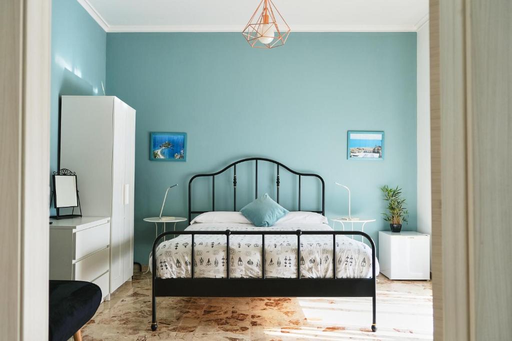 Un dormitorio con una cama con una pared azul. en SoStanza - Rooms in Catania, en Catania