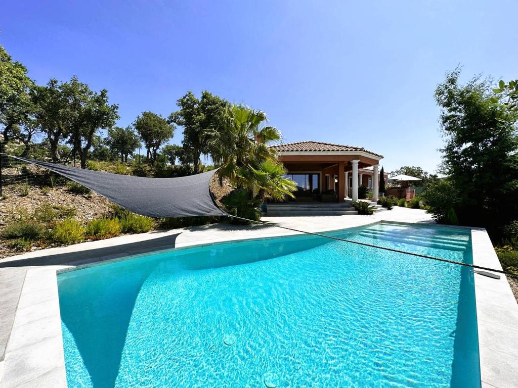 a hammock in front of a house with a swimming pool at Villa Azur climatisée pour 6 personnes avec piscine et belle vue mer à La Londe les Maures in La Londe-les-Maures