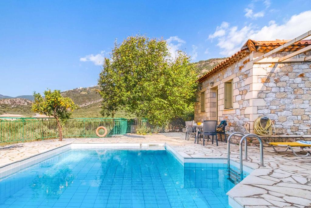 a swimming pool in front of a stone house at Villa Palataki I in Kardamyli