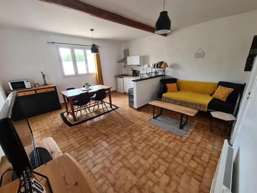 un salon avec un canapé jaune et une cuisine dans l'établissement Grand gîte avec jacuzzi à La Turballe, à La Turballe
