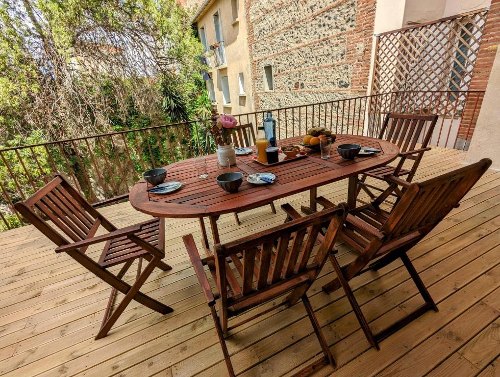 une table et des chaises en bois sur une terrasse en bois dans l'établissement Proche centre ville avec une belle terrasse, à Perpignan