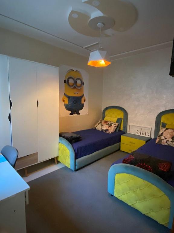 a bedroom with two beds and a minion on the wall at Airport house hotel in Derroua