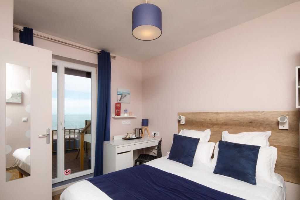 a bedroom with a bed and a view of the ocean at Saint Aubin Logis Hôtel & Restaurant in Saint-Aubin-sur-Mer