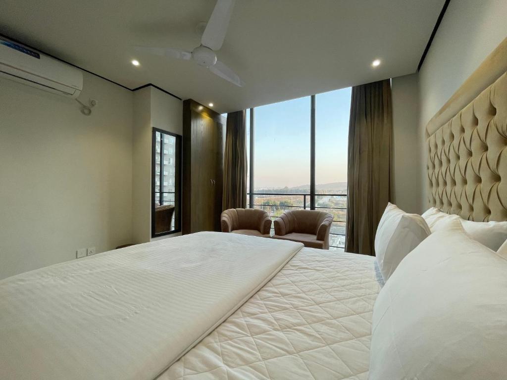 a bedroom with a large bed and a large window at Sense Luxury II - 2 bed Apartment in Islamabad