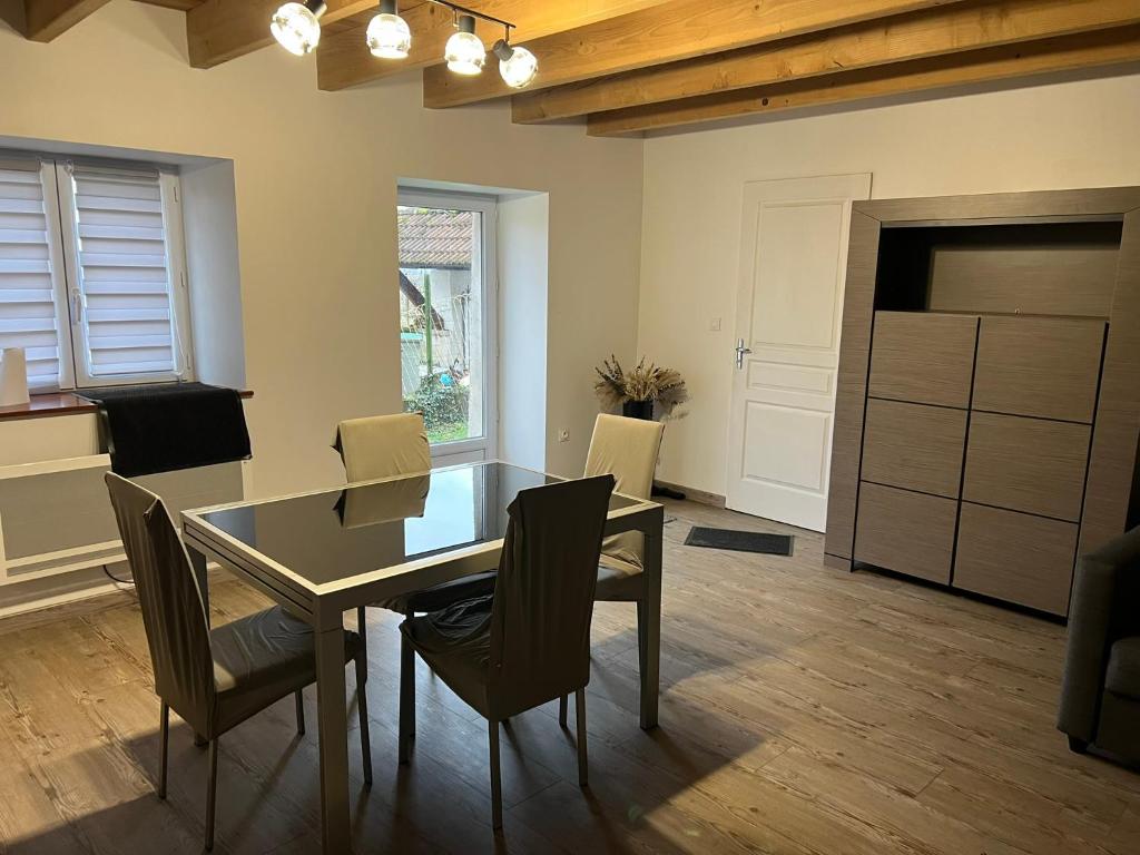 a dining room with a glass table and chairs at Chez Laura et Alex in Geville