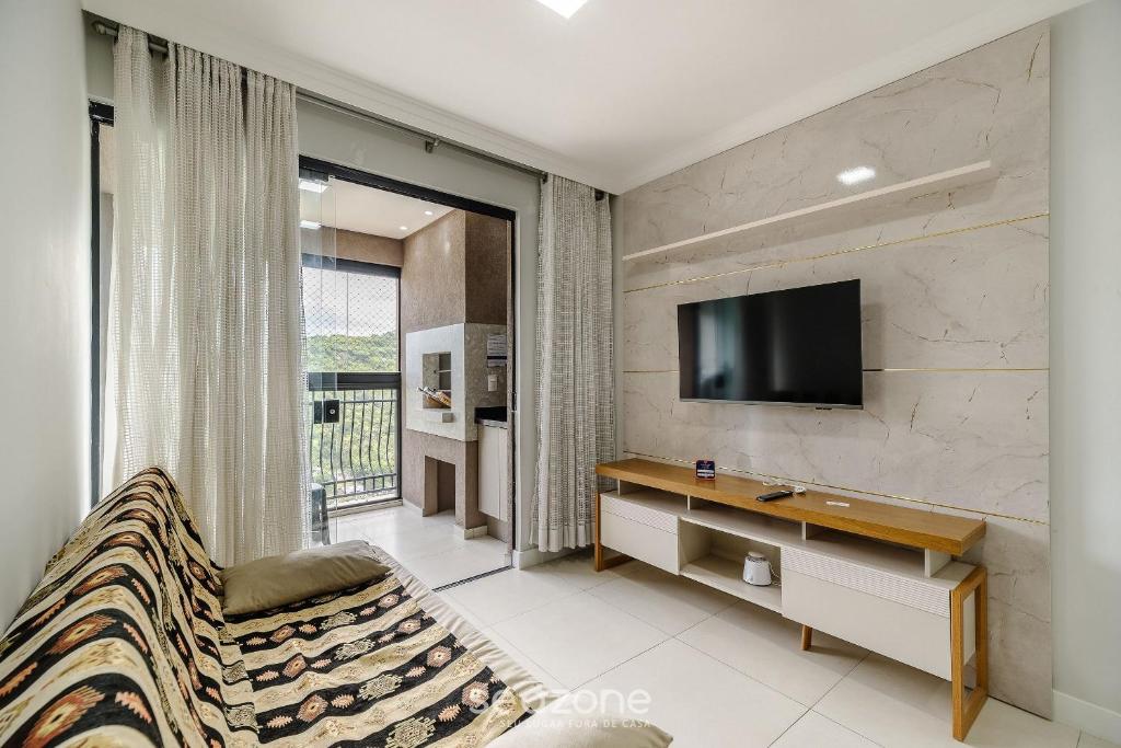 Una sala de estar con un televisor en la pared. en Apto 2H c/ parrilla a 750m de la playa RVN2003, en Itapema