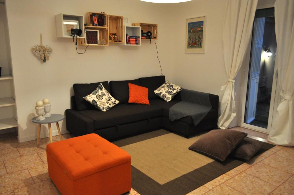 sala de estar con sofá negro y silla naranja en Domus Caffarella, en Roma